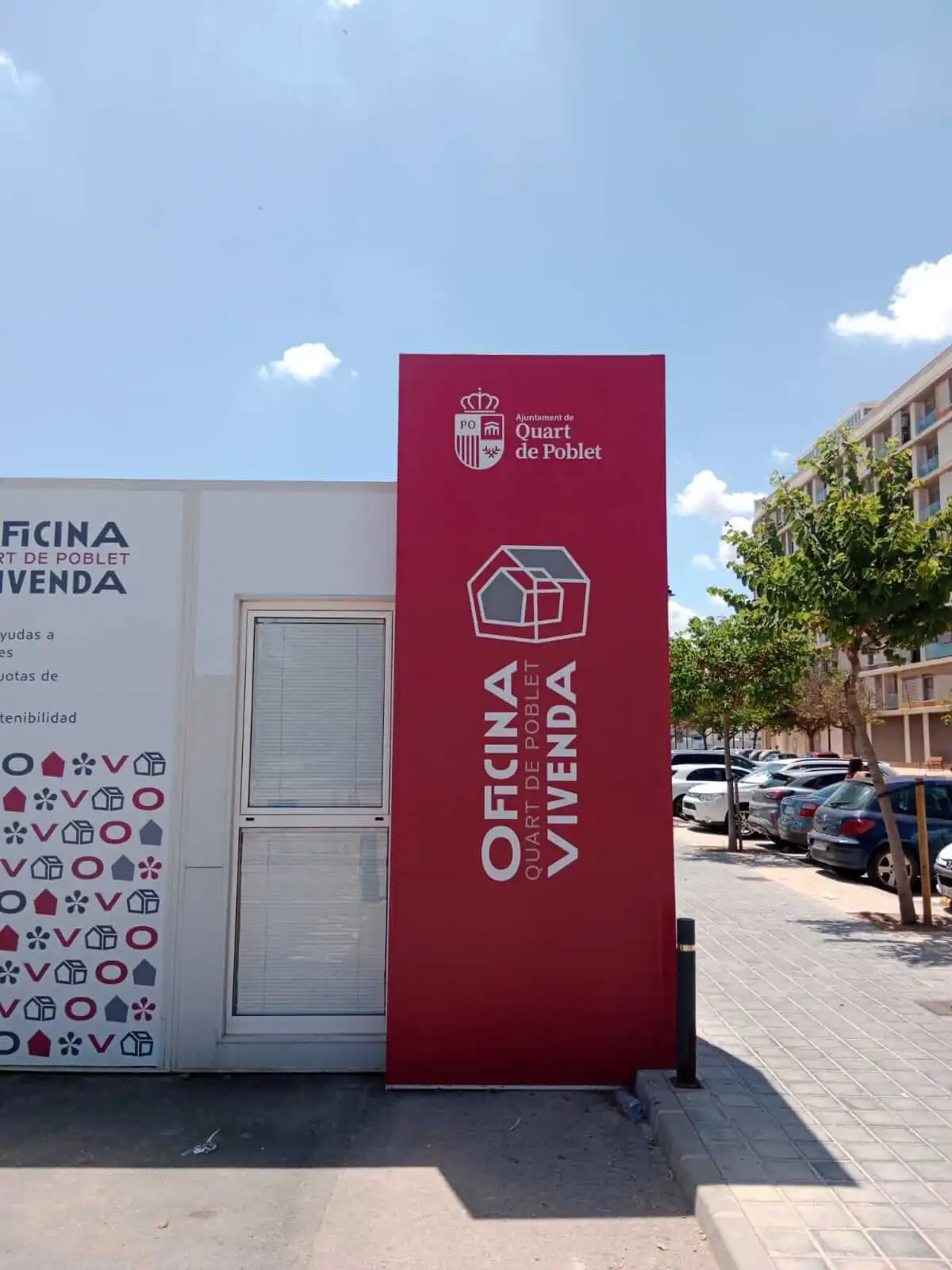 Tòtem vermell de l’Oficina d’Habitatge de Quart de Poblet amb escut municipal.